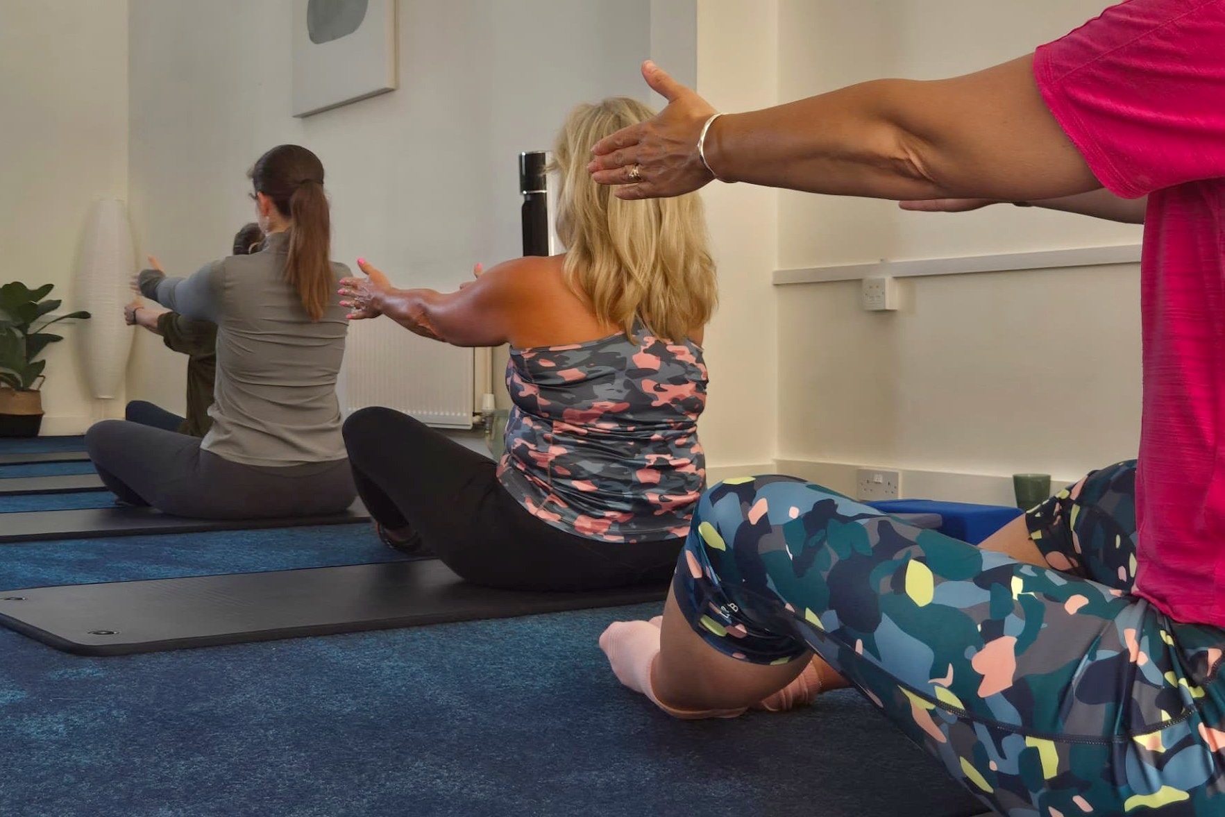 A small Pilates class working through a seated exercise on mats in Camilla's studio